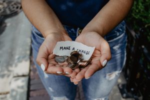 Hände mit Münzen und "Make a change"-Botschaft
